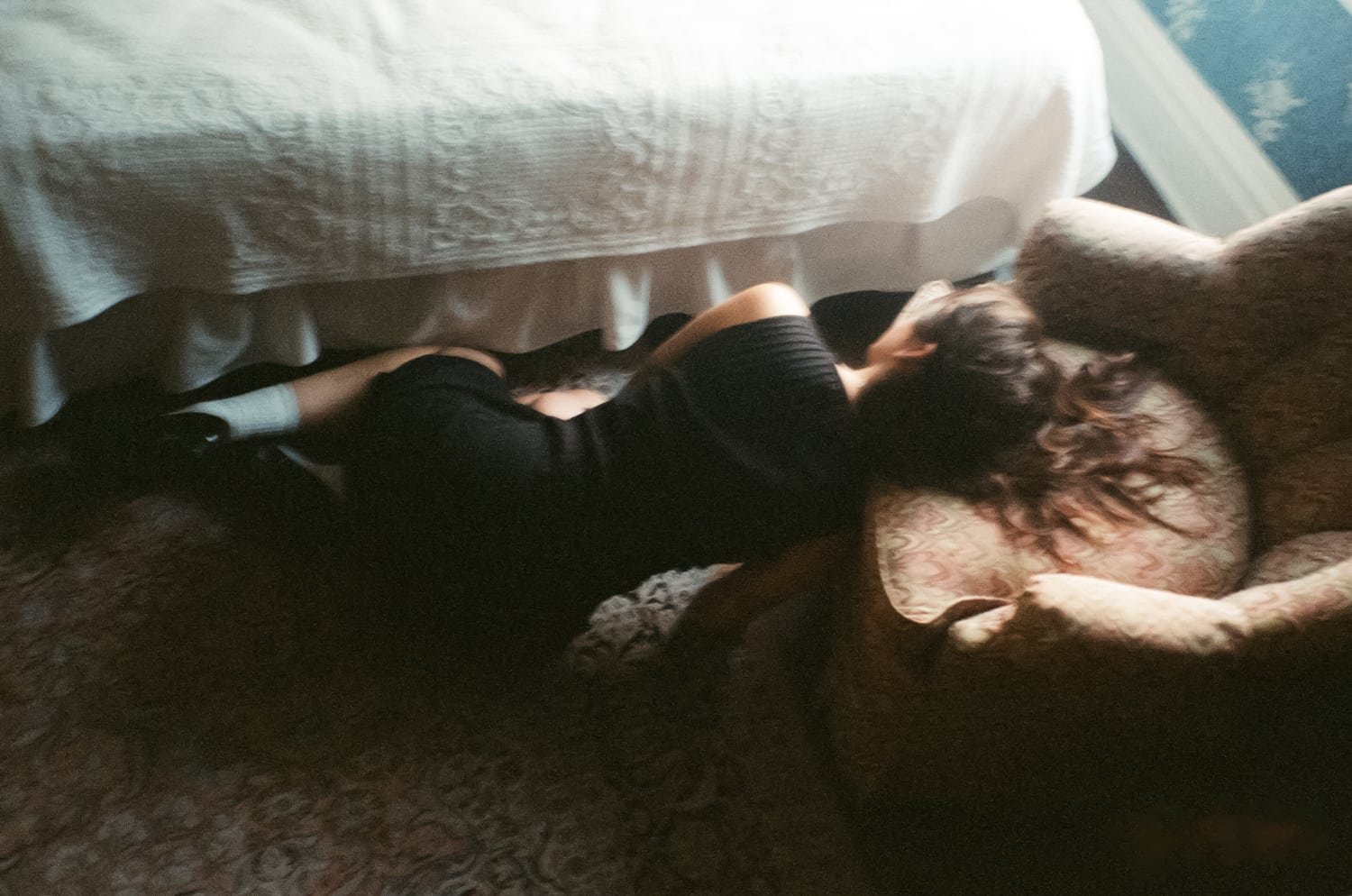 Figure resting on the floor by a bed