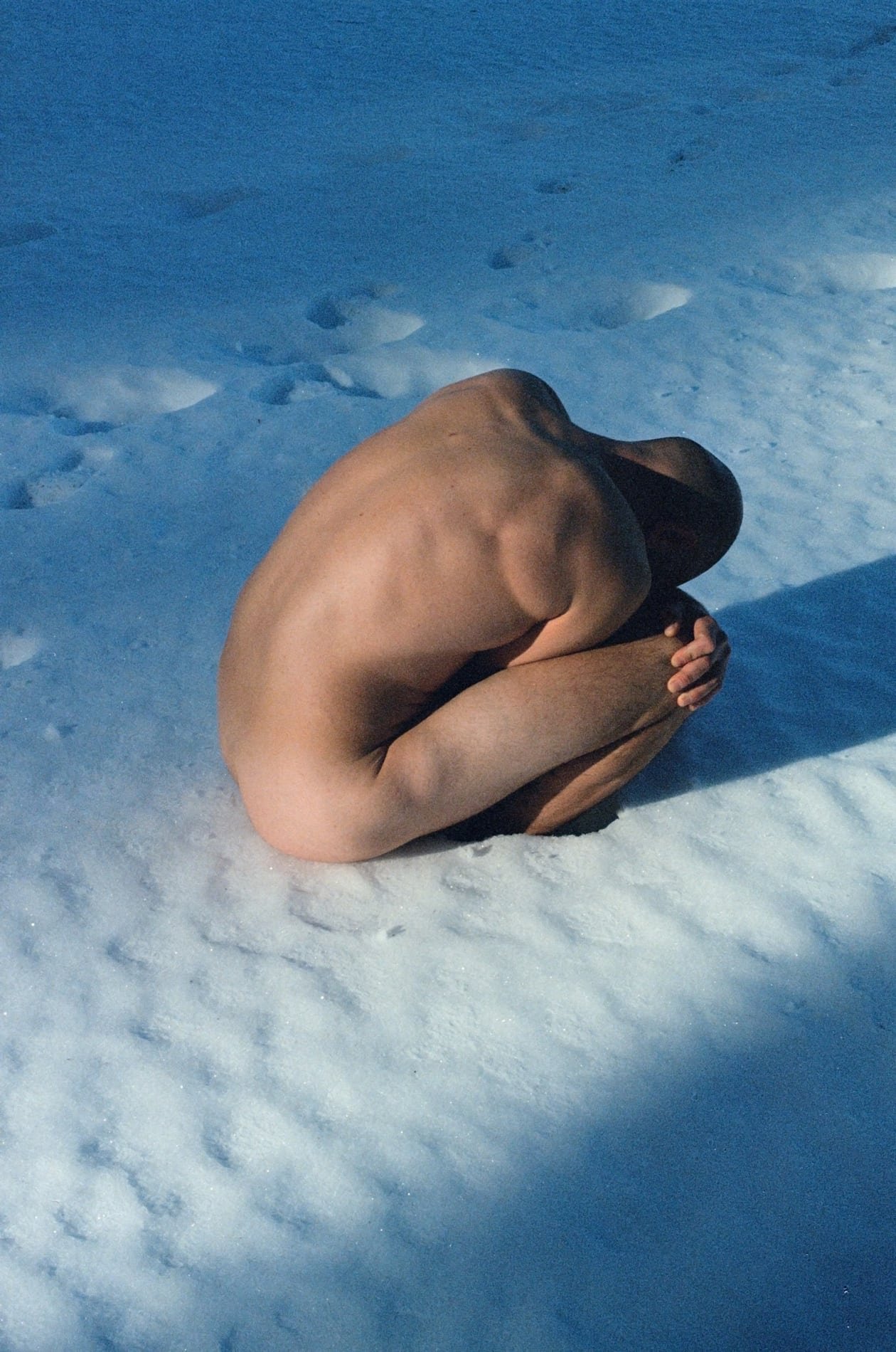 Figure curled in the snow, blue light